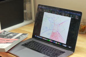 MacBook Pro แสดงแบบร่างสถาปัตยกรรม พร้อมหนังสือสถาปัตยกรรม